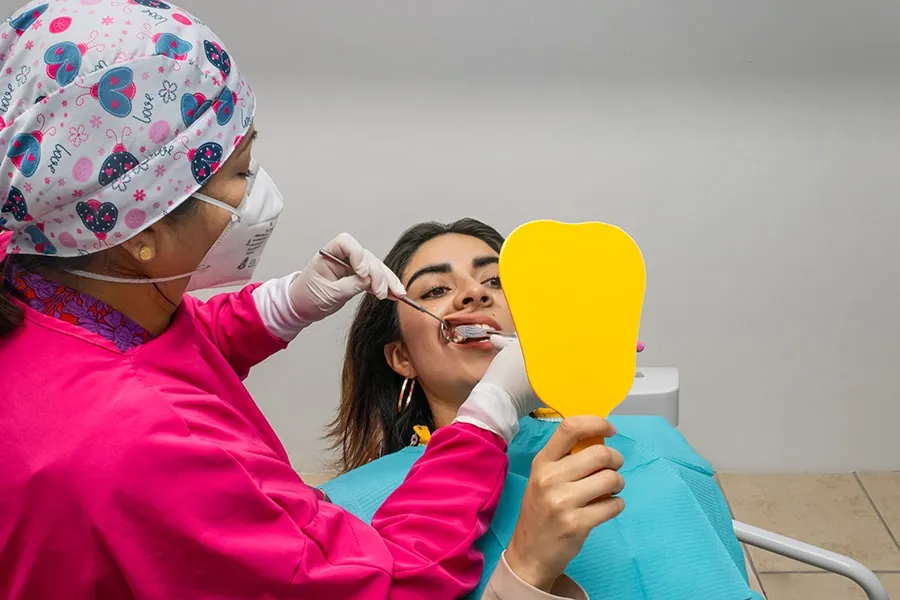 La doctora muestra a una paciente el resultado con un espejo